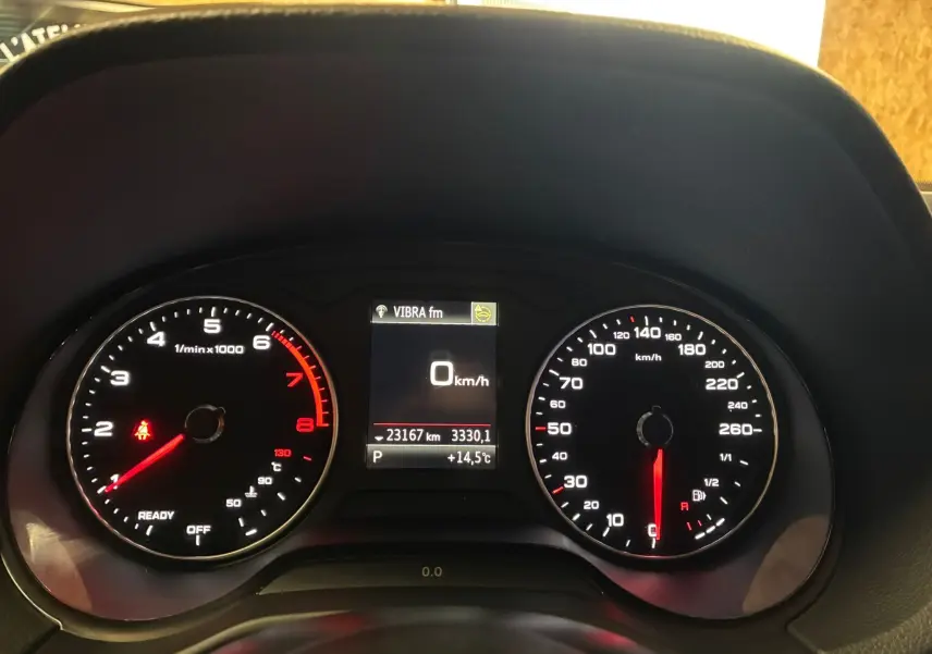 Tableau de bord de l'Audi Q2 noir, affichant compte-tours, vitesse à 0 km/h et écran central avec température et kilométrage.