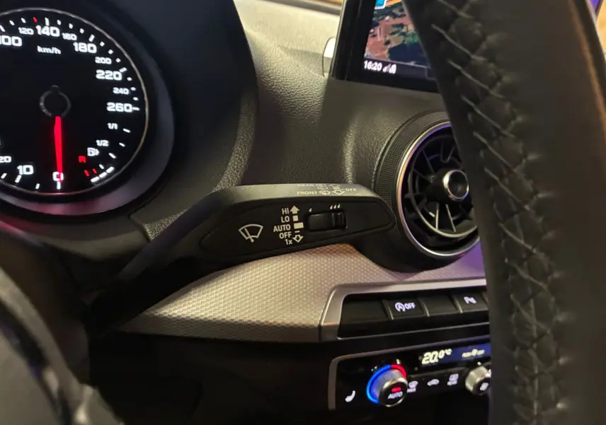 Vue rapprochée du tableau de bord noir de l'Audi Q2 2023, avec commandes d'essuie-glace et ventilation circulaire.