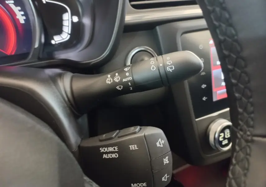 Gros plan sur les commandes au volant du Renault Kadjar gris foncé, avec affichage digital et écran tactile en arrière-plan.