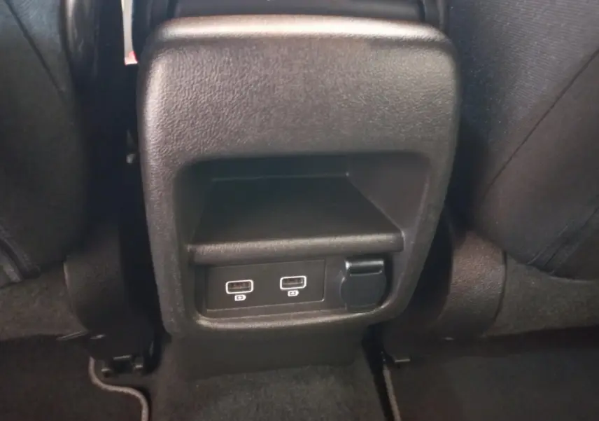 Prise USB double et prise 12V noire vue de près à l'arrière des sièges noirs du Renault Kadjar gris foncé.