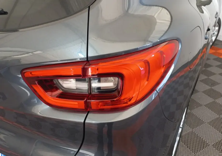 Gros plan sur le feu arrière droit rouge du Renault Kadjar gris foncé, avec partie latérale et reflet au sol.
