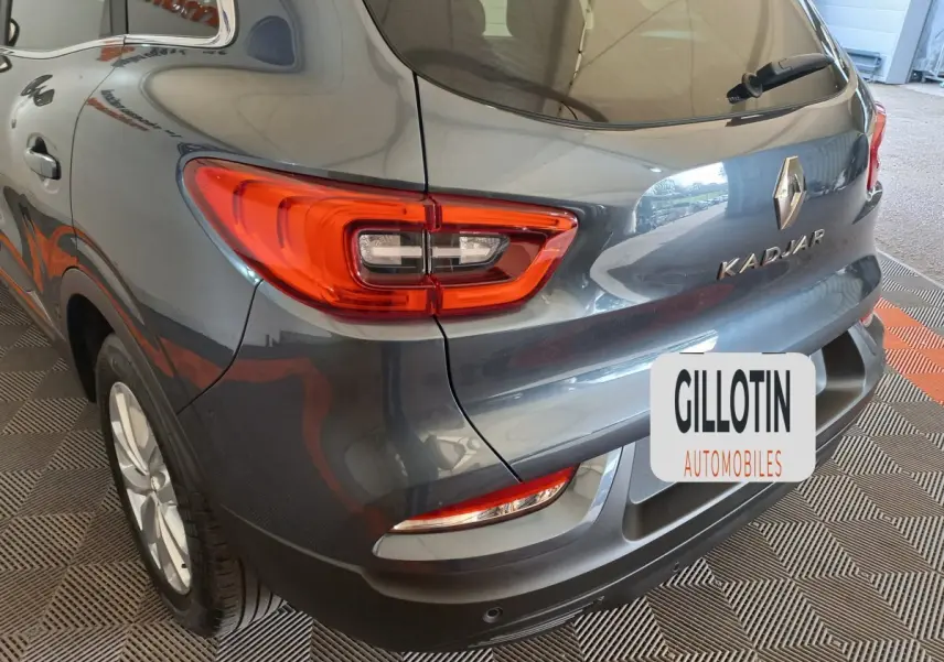 Vue 3/4 arrière droite d’un Renault Kadjar gris foncé avec feux arrière LED et logo visible sur un sol damier.