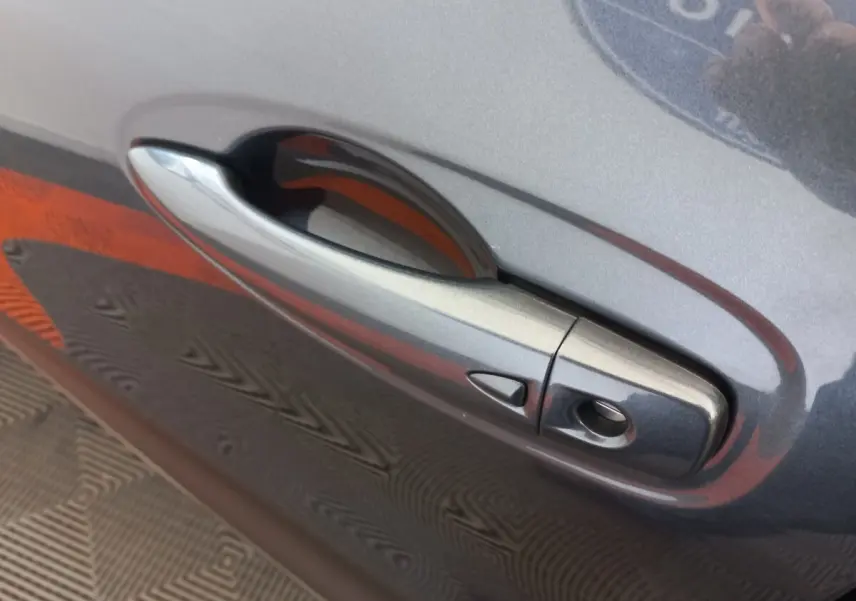 Poignée de porte gris foncé côté droit du Renault Kadjar Business Blue dCi 115 EDC 2022 avec bouton de déverrouillage.