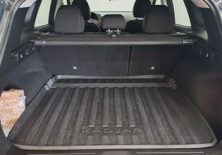 Coffre ouvert d’un Renault Kadjar gris foncé, vue arrière montrant la protection de coffre avec logo Kadjar.