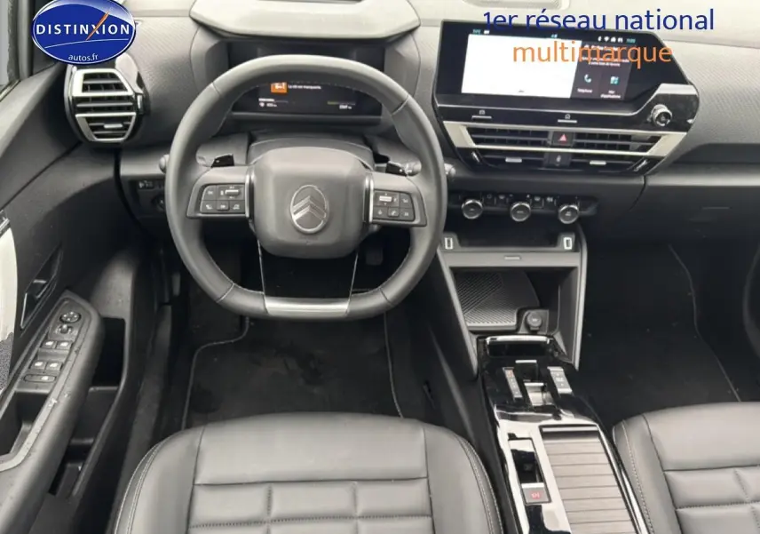 Vue intérieure avant centrée sur le volant cuir noir et la console centrale brillante de la Citroën C4 hybride 2025.