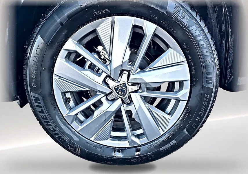 Gros plan sur la jante alu argentée du Peugeot 5008 Hybrid 145 allure e-dcs6 avec pneu Michelin noir.
