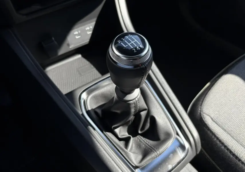 Gros plan sur le levier de vitesses manuel du Renault Captur blanc nacré 2025, entouré de cuir noir et chrome.