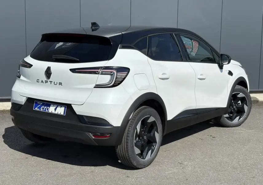 Vue 3/4 arrière droite du Renault Captur blanc nacré avec toit noir étoilé et jantes noires distinctives.