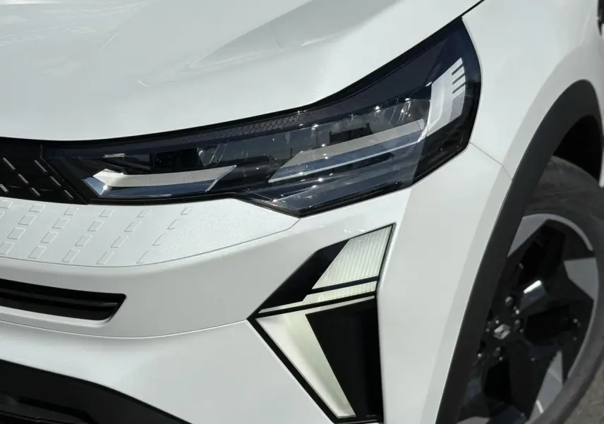Gros plan sur le phare avant droit du Renault Captur Blanc Nacré 2025 avec jante aluminium noire.