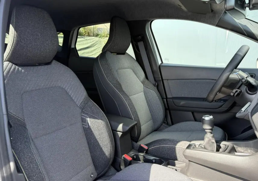 Vue intérieure côté droit du Renault Captur 2025, sièges tissu gris et levier de vitesses manuel visible.
