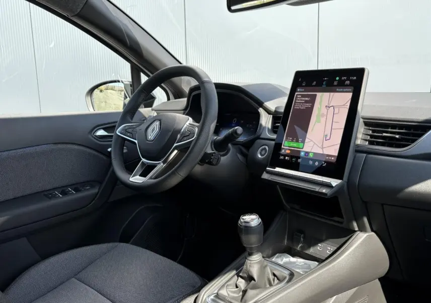 Intérieur côté conducteur du Renault Captur 2025 avec volant multifonction, boîte manuelle et écran tactile vertical.