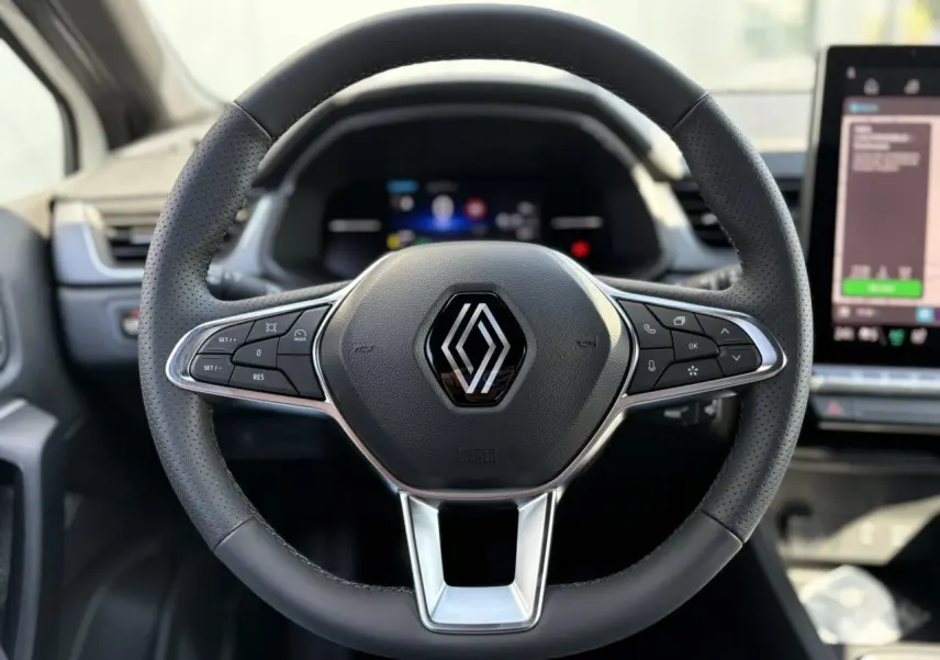 Volant en cuir noir avec commandes intégrées et logo Renault au centre, intérieur du Renault Captur 2025.