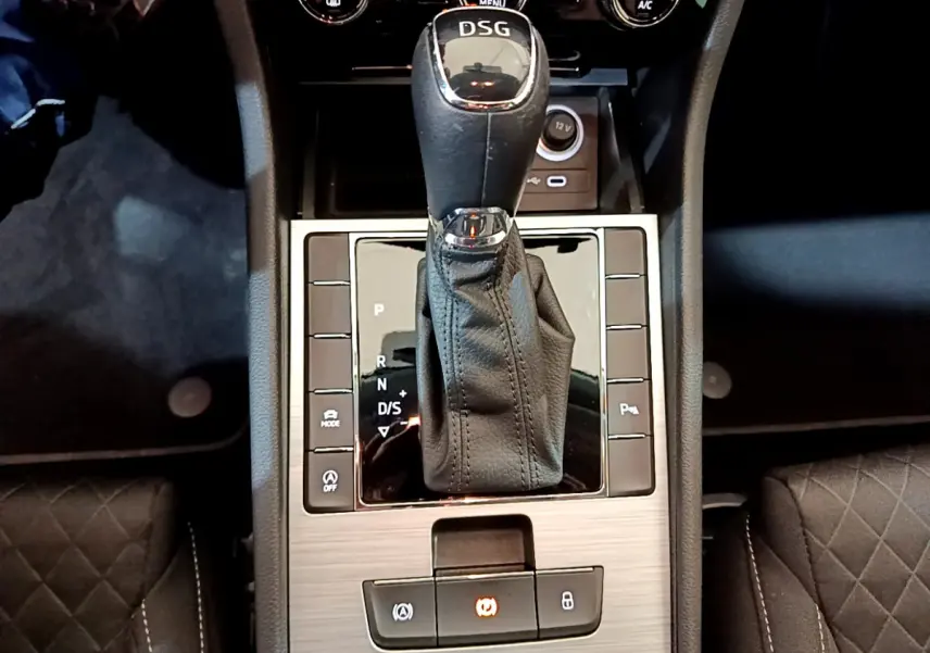 Le levier de vitesse DSG noir et chrome de la Skoda Superb 2020, vu de dessus, entouré de commandes sur console bois clair.