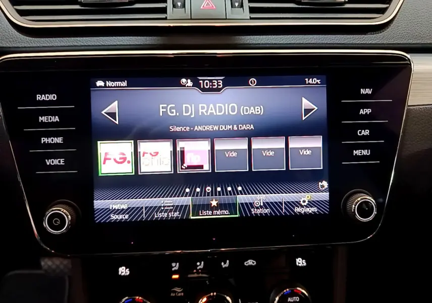 Écran tactile central de la Skoda Superb 2020 affichant la radio DAB, entouré de commandes noires et bois clair.