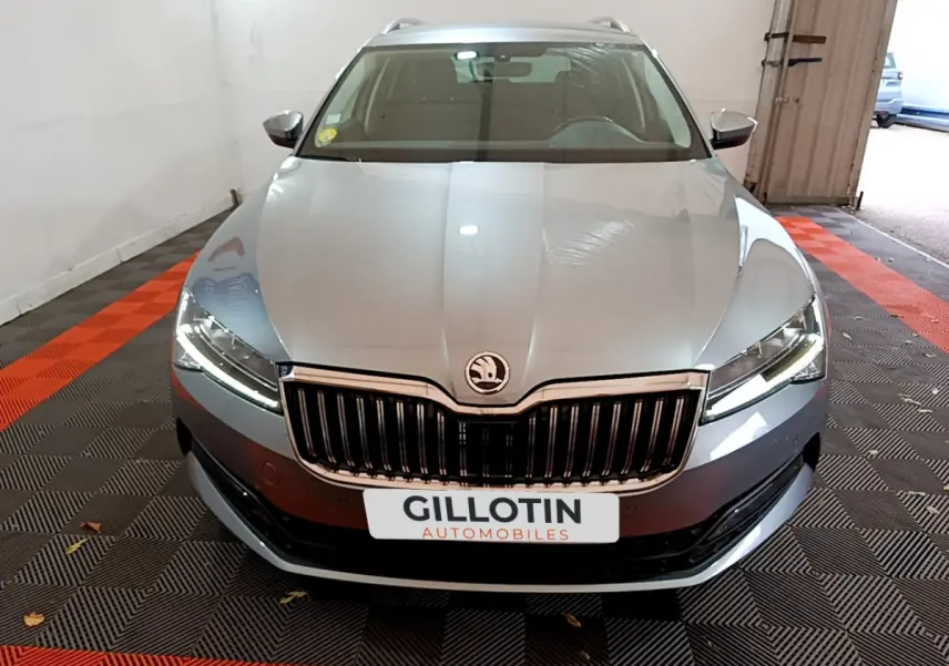 Vue frontale d'une Skoda Superb gris clair avec calandre chromée et phares LED allumés en intérieur.