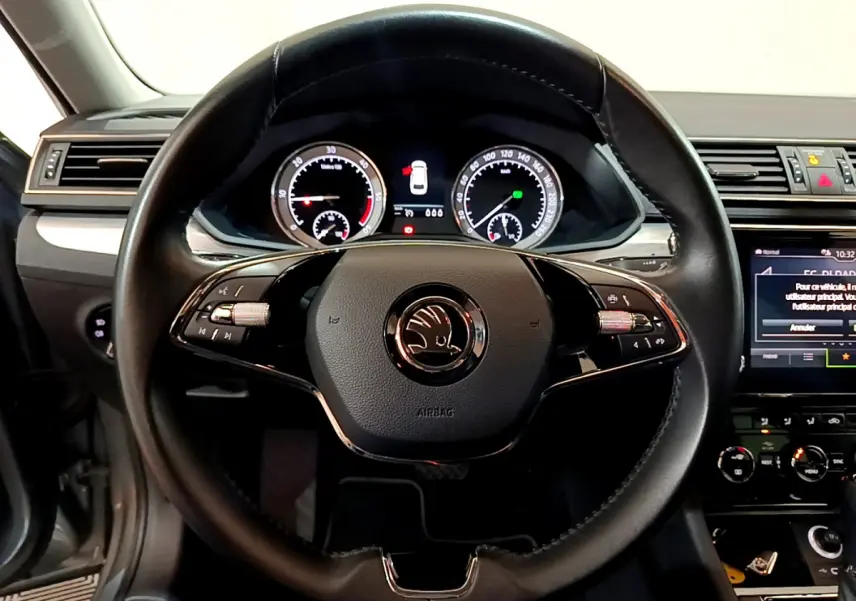 Vue centrée sur le volant cuir noir de la Skoda Superb 2020, avec tableau de bord digital et écran tactile visible à droite.