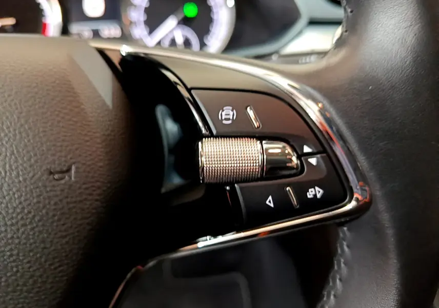 Gros plan sur les commandes à droite du volant cuir d'une Skoda Superb 2020, avec molette métallique et boutons noirs.