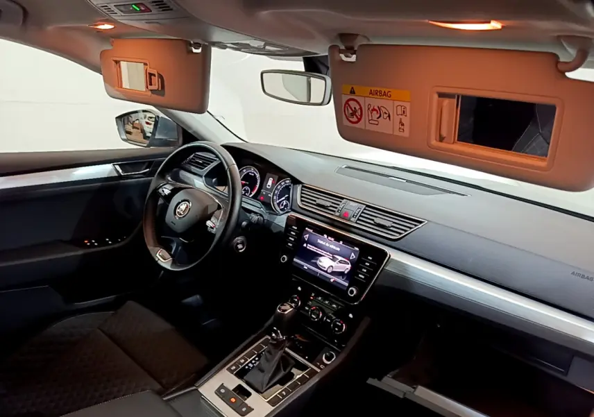 Intérieur noir de la Skoda Superb 2020 vu côté conducteur, avec tableau de bord et écran tactile central allumés.