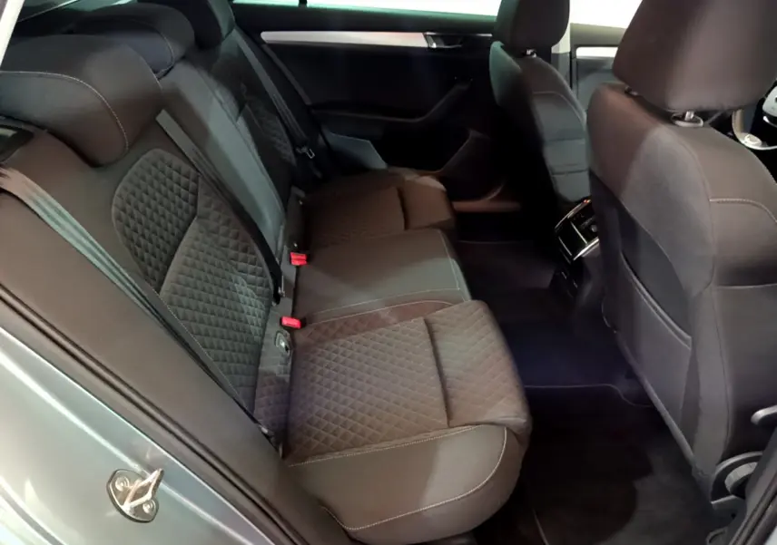 Vue intérieure côté arrière droit de la Skoda Superb 2020 gris clair, sièges arrière en tissu noir matelassé avec surpiqûres.