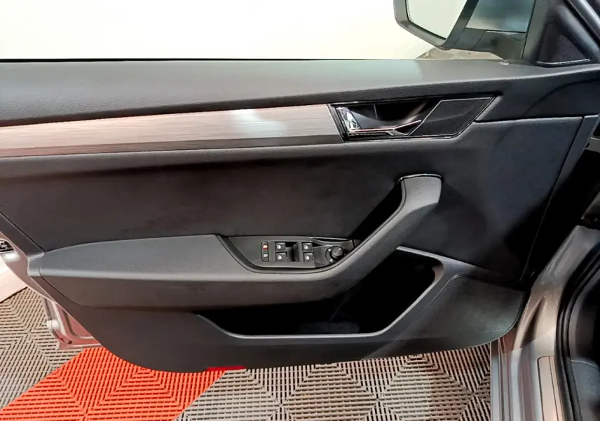 Vue côté gauche de la porte avant gris clair d'une Skoda Superb 2020 avec commandes électriques des vitres et insert bois.