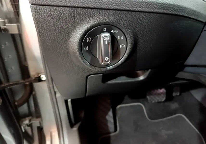 Gros plan sur la commande des phares à gauche du volant dans l'habitacle gris foncé de la Skoda Superb 2020.