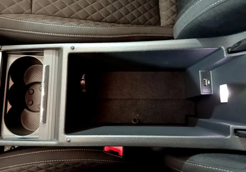 Vue plongeante sur le rangement central et porte-gobelets avec USB de la Skoda Superb gris clair 2020 intérieur cuir noir.