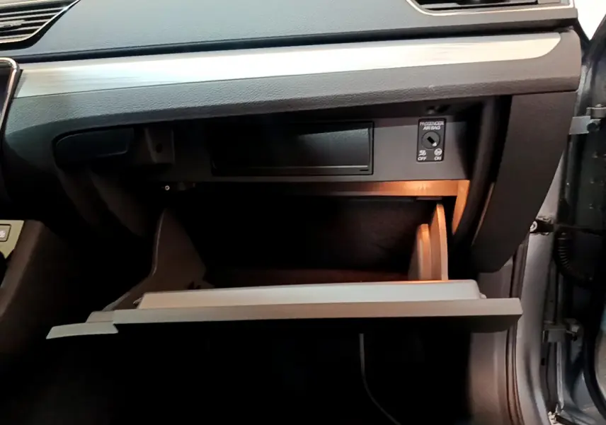 Gros plan sur la boîte à gants ouverte côté passager d'une Skoda Superb gris clair avec éclairage intérieur doux.