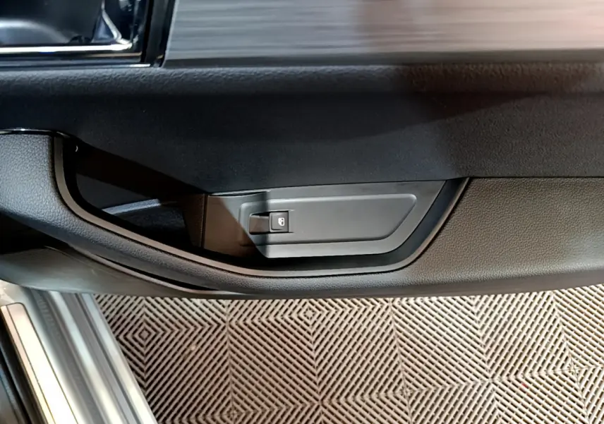 Gros plan sur la poignée intérieure de porte côté conducteur d'une Skoda Superb gris clair, avec bouton de verrouillage.