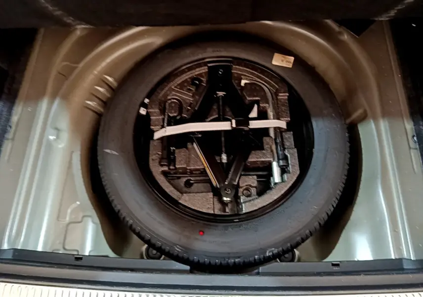 Vue plongeante sur la roue de secours et le kit d'outils dans le coffre gris clair d'une Skoda Superb 2020.