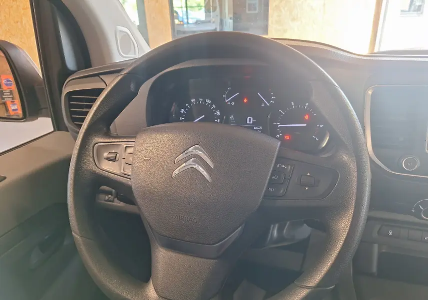 Vue rapprochée du volant noir de la Citroën Jumpy 2.0 BlueHDi 120 Club 2020 avec tableau de bord allumé.