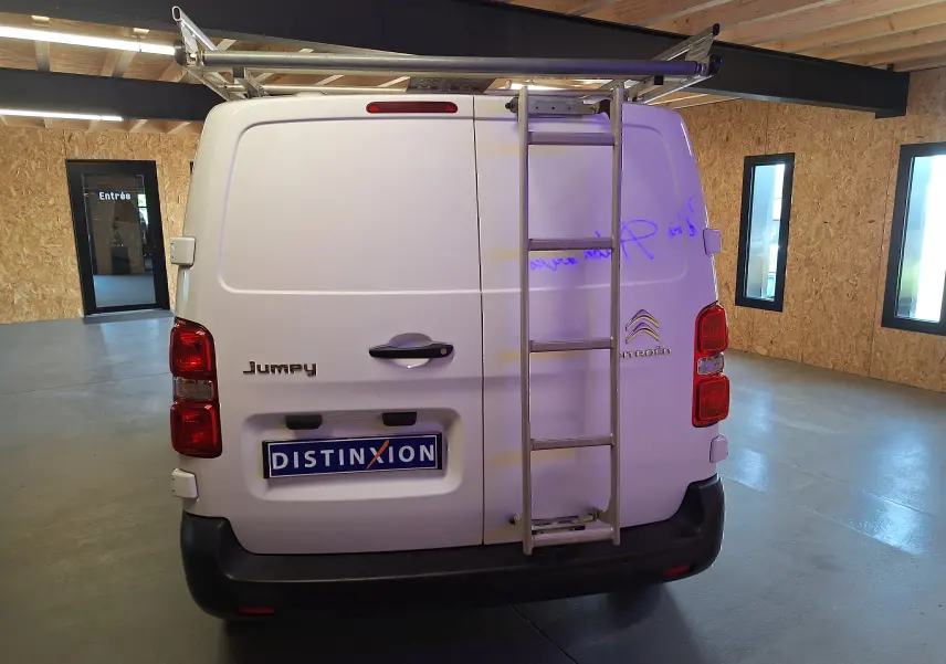 Vue arrière d'un utilitaire blanc Citroën Jumpy 2.0 BlueHDi 120 Club avec échelle métallique fixée sur la porte droite.