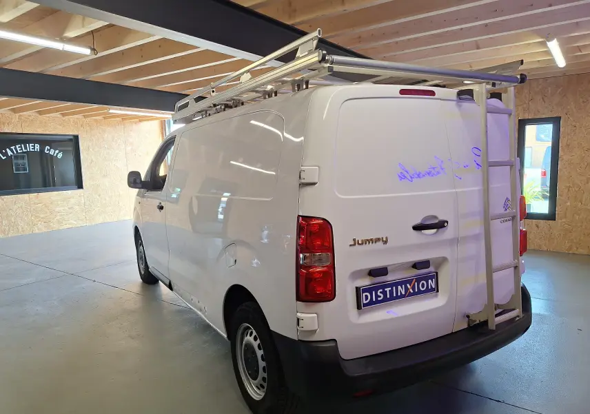 Vue 3/4 arrière droite d'un utilitaire blanc Citroën Jumpy 2.0 BlueHDi 120 avec galerie et échelle sur le toit.