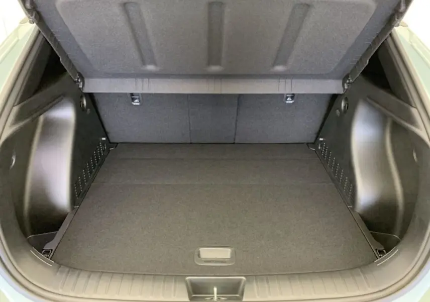 Coffre ouvert du Hyundai Kona Hybrid 2025 en Mirage Green, vue intérieure montrant un espace de chargement propre et spacieux.