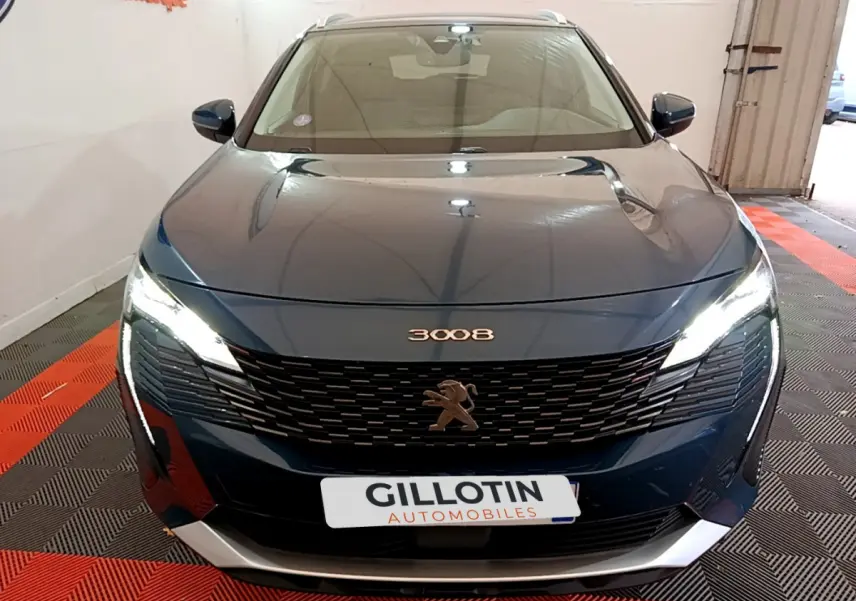Vue frontale d'un Peugeot 3008 bleu avec calandre noire et phares LED allumés dans un garage.