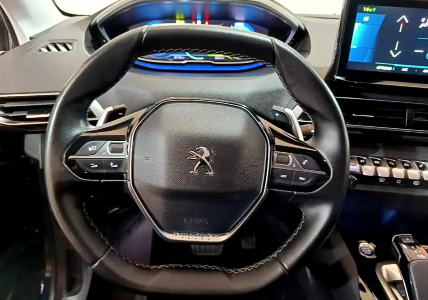 Vue rapprochée du volant cuir noir de la Peugeot 3008 bleu, avec tableau de bord numérique et écran tactile visible.