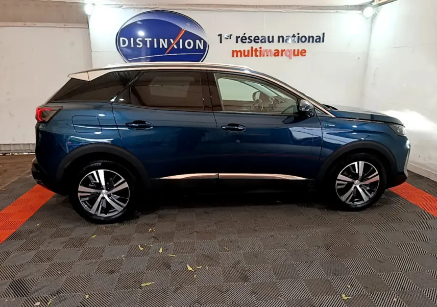 Profil droit d'un Peugeot 3008 hybride rechargeable bleu 2021 avec jantes alliage et vitres teintées en intérieur showroom.