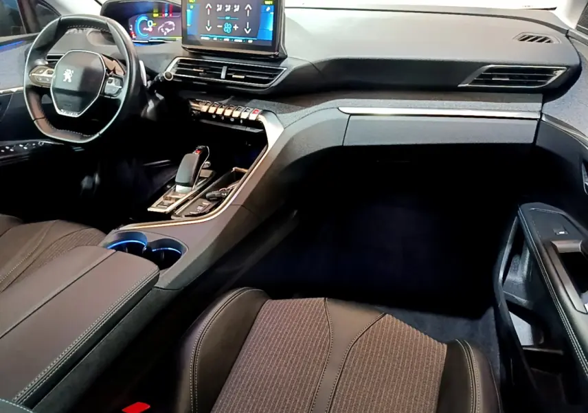 Intérieur du Peugeot 3008 hybride 2021 vu côté passager, tableau de bord moderne avec écran tactile et volant compact.