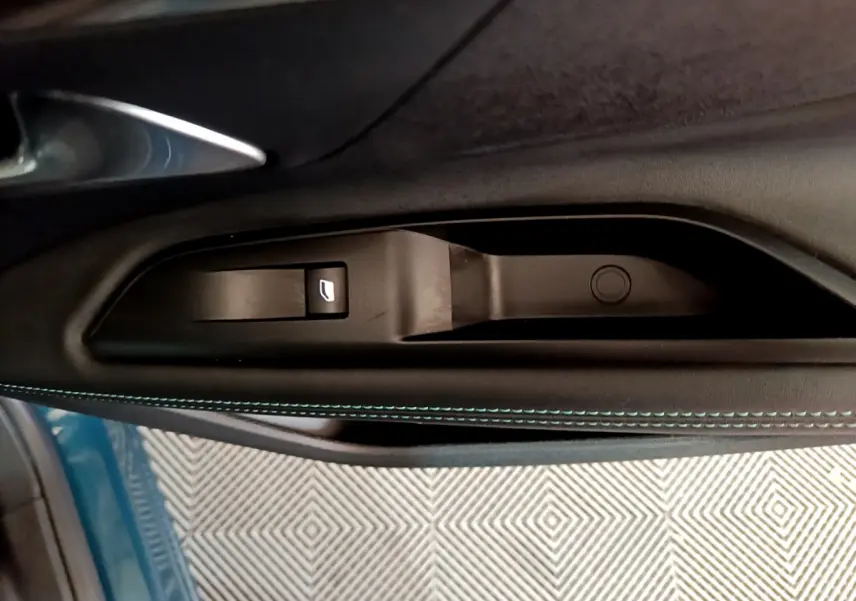 Poignée intérieure côté gauche avec bouton de lève-vitre sur porte bleu métallisé d’un Peugeot 3008 hybride 2021