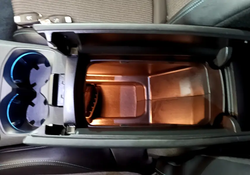 Vue plongeante sur le rangement central éclairé et les porte-gobelets bleutés du Peugeot 3008 hybride rechargeable 2021.