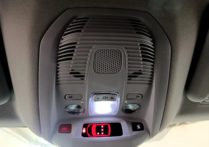 Vue intérieure du plafonnier gris clair du Peugeot 3008 hybride avec boutons SOS et éclairage central allumé.