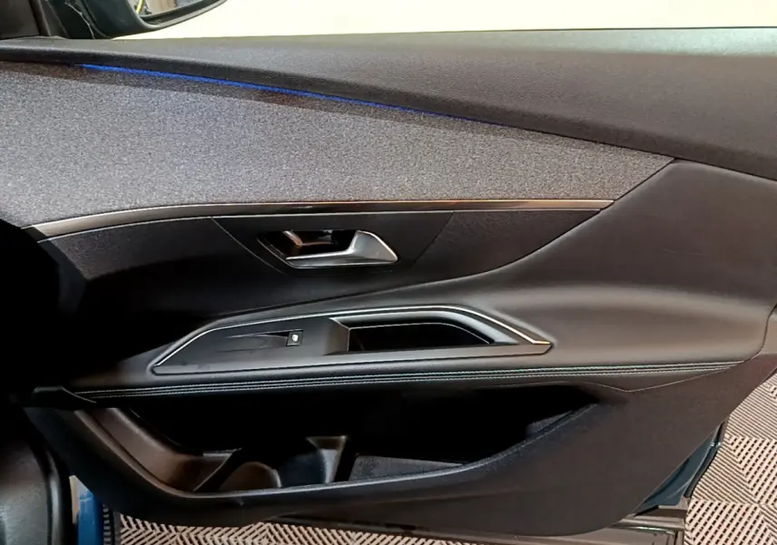 Vue côté gauche de la porte intérieure noire du Peugeot 3008 bleu, avec poignée et bandeau décoratif argenté.