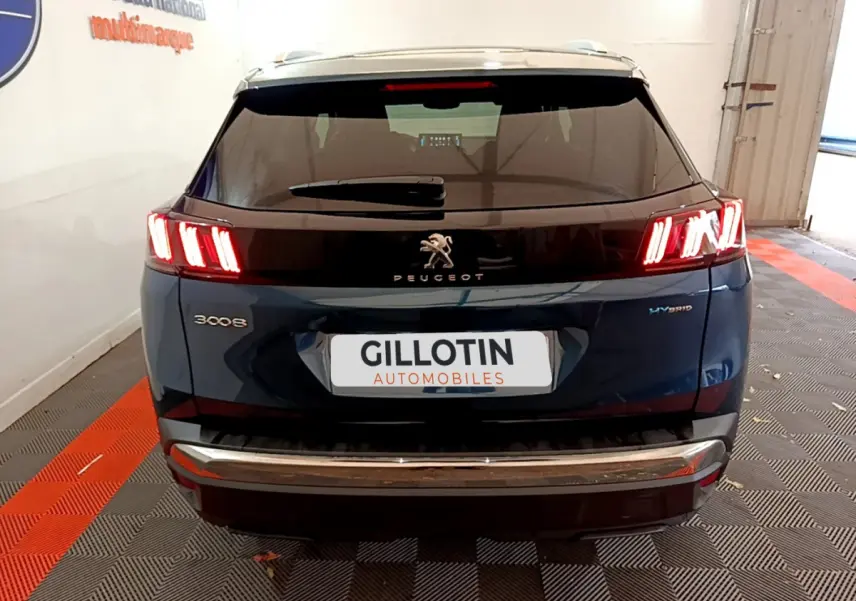 Vue arrière d'un Peugeot 3008 bleu hybride rechargeable avec feux LED allumés dans un garage.