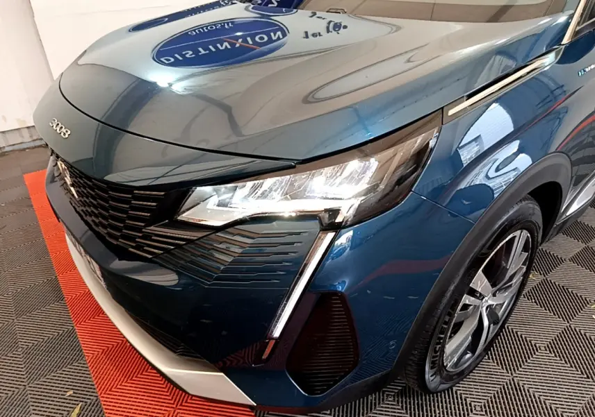 Vue 3/4 avant droit d'un Peugeot 3008 bleu hybride rechargeable avec phares LED et calandre noire distinctive.