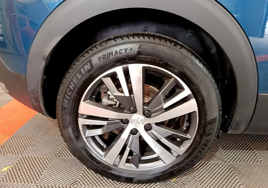 Gros plan sur la roue avant gauche d’un Peugeot 3008 bleu, avec jante alliage et pneu Michelin Primacy 4.