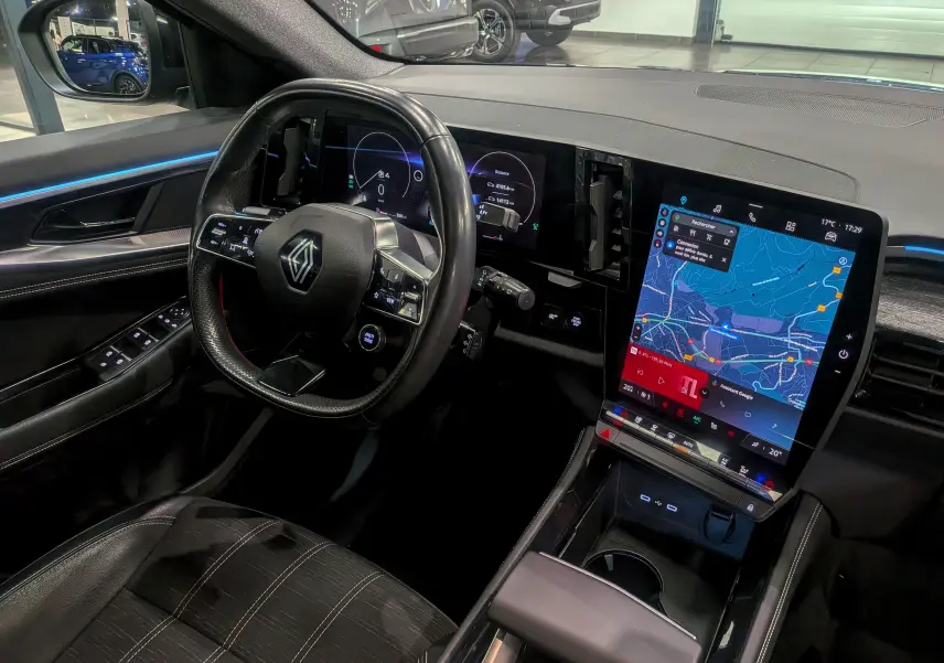 Intérieur du Renault Austral 2024, vue côté conducteur, volant multifonction et grand écran tactile vertical avec navigation.