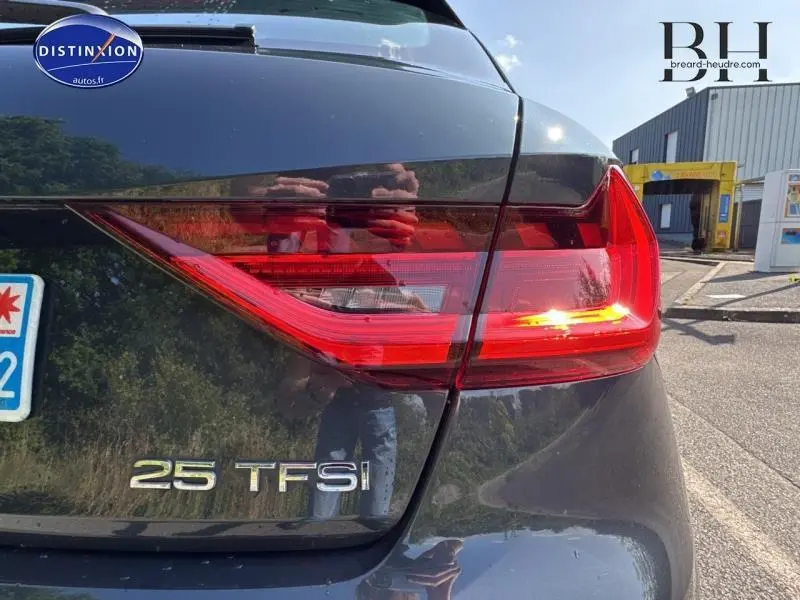 Gros plan sur le feu arrière droit et le logo 25 TFSI d'une Audi A1 Sportback noir Mythic métallisé.