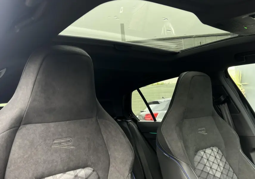 Vue intérieure montrant les sièges sport R-Line en alcantara gris avec toit ouvrant panoramique sur une Volkswagen Golf VIII noire.