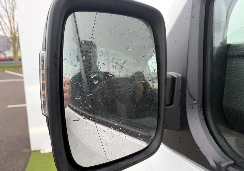 Rétroviseur gauche du Renault Trafic Fourgon blanc glacier 2025 avec clignotant intégré et traces de pluie.