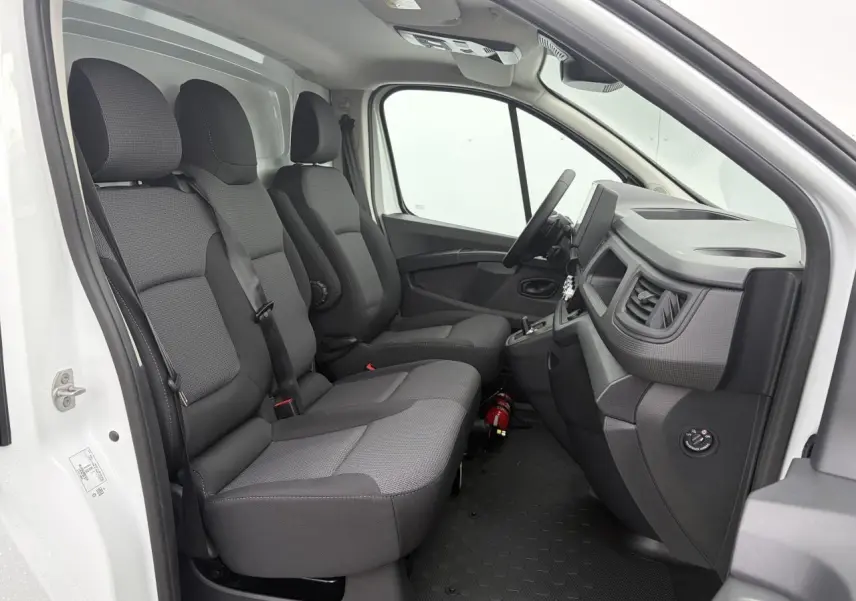 Vue intérieure côté conducteur du Renault Trafic Fourgon blanc glacier, montrant la banquette passager et le tableau de bord.