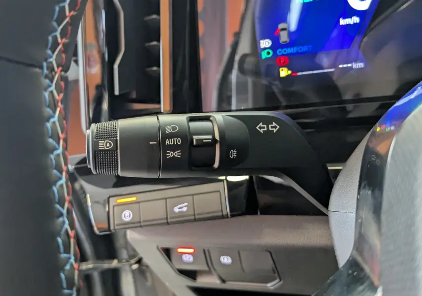Gros plan sur la commande des feux et clignotants à gauche du volant du Renault Austral gris schiste, tableau de bord numérique visible.